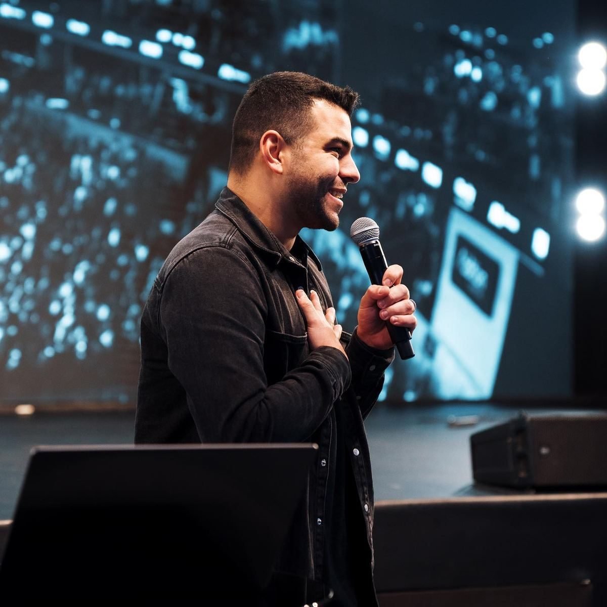 Léo Neves falando ao microfone num palco